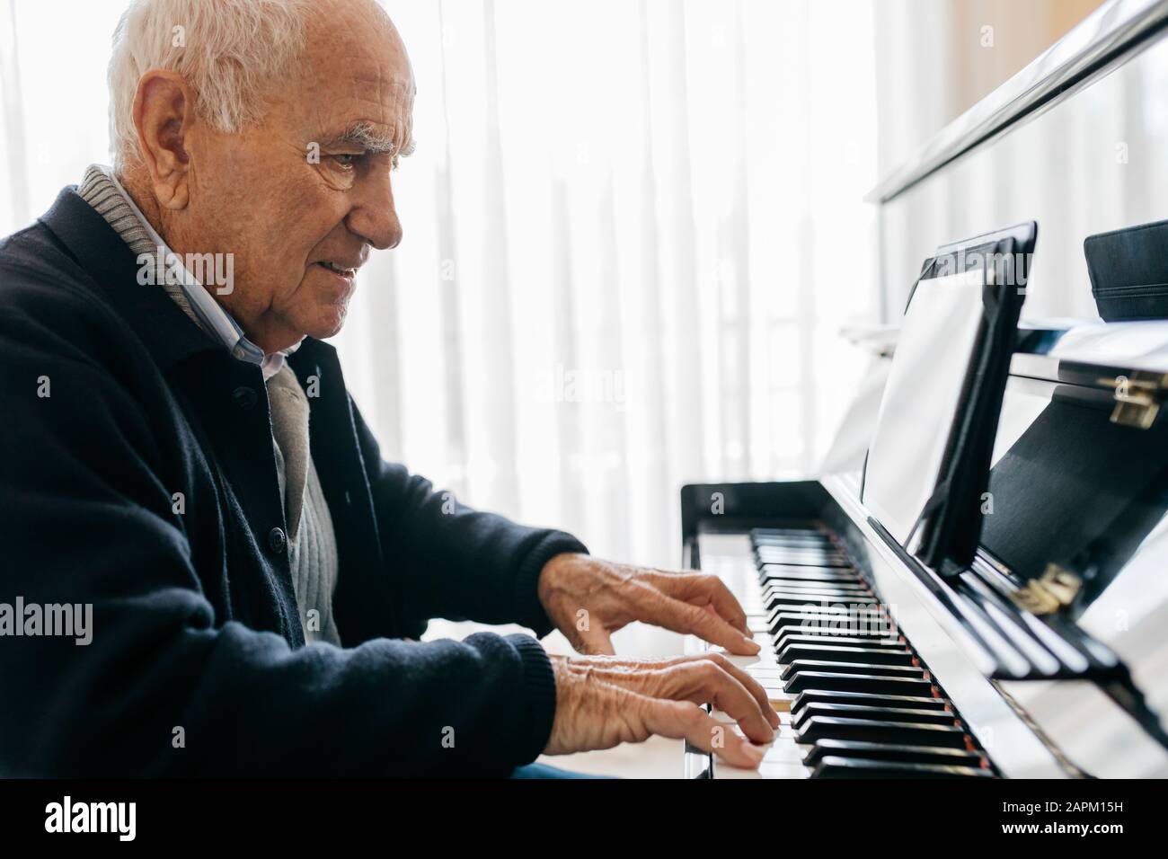 Hombre mayor sentado en silla de ruedas tocando el piano en casa Fotografía  de stock - Alamy