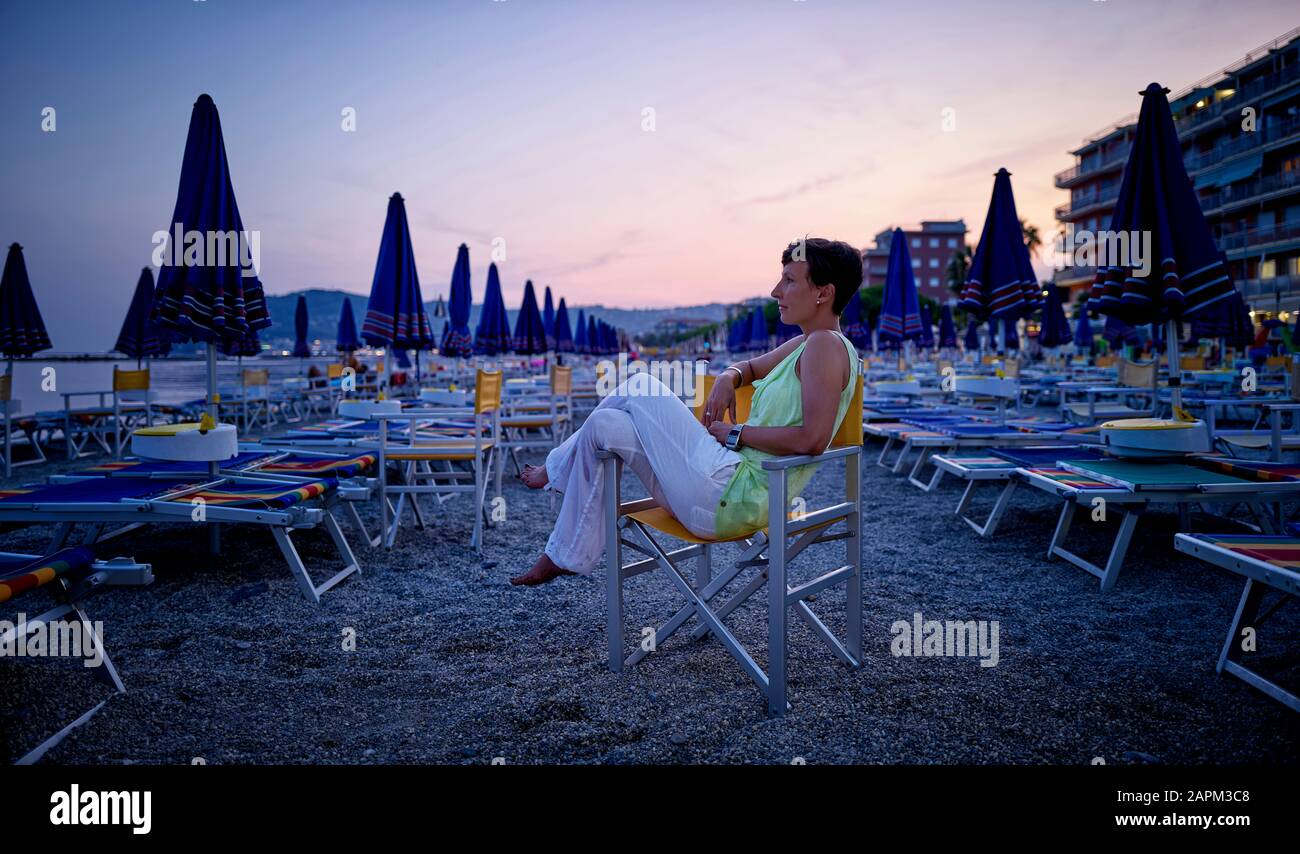 Mujer madura en la playa al atardecer, San Bartolomeo al Mare, Italia Foto de stock