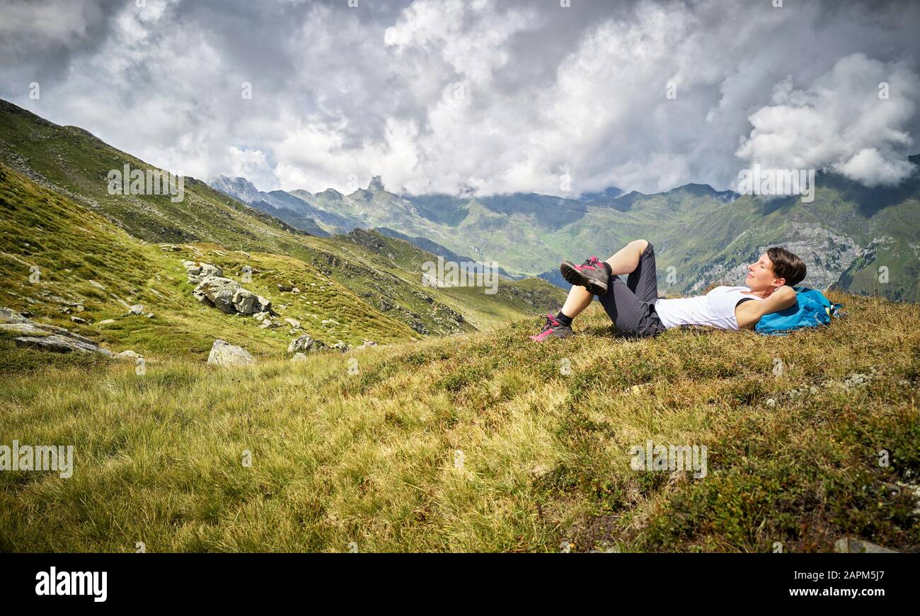 Mujer que tiene un descanso de senderismo en la pradera alpina, Passeier Valley, Tirol del Sur, Italia Foto de stock