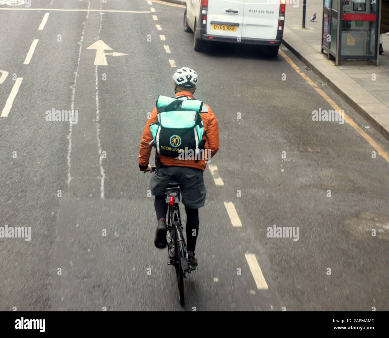 Eco Runners una ciclista de soluciones de entrega respetuosa con el medio ambiente en bicicleta en medio de la carretera Foto de stock