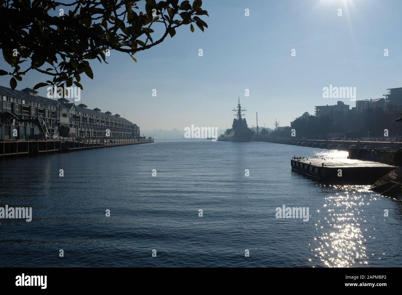 El muelle Finger Wharf y el barco marino real australiano en Garden Island visto a través de una niebla matutina en el puerto de Sydney, Woolloomooloo, Sydney, Australia Foto de stock