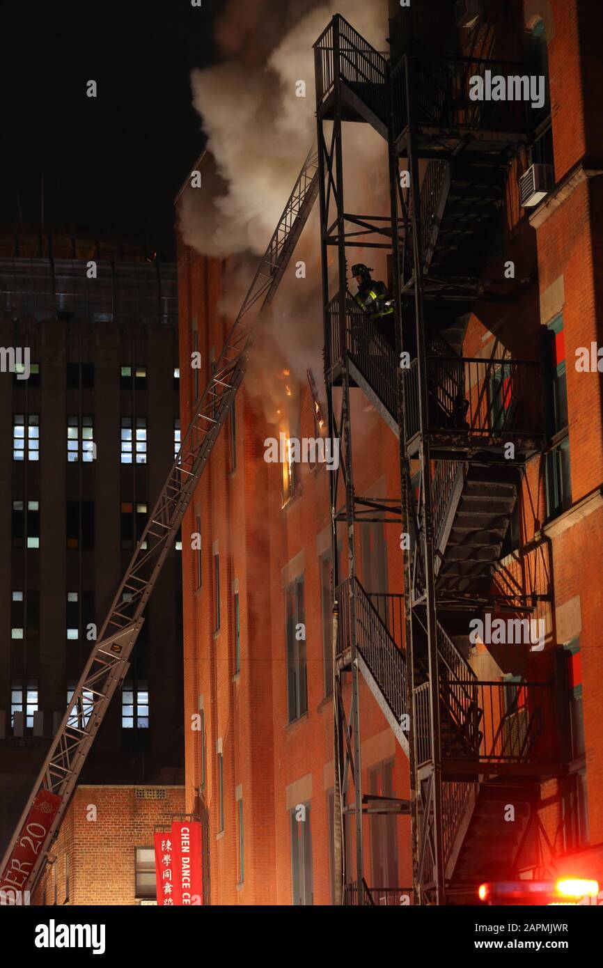 (Nueva York, NY, 23 de enero de 2020) 9pm. Un bombero que asciende a un incendio escape de un centro comunitario en el fuego en 70 Mulberry St. El fuego estalló en el 4 Foto de stock