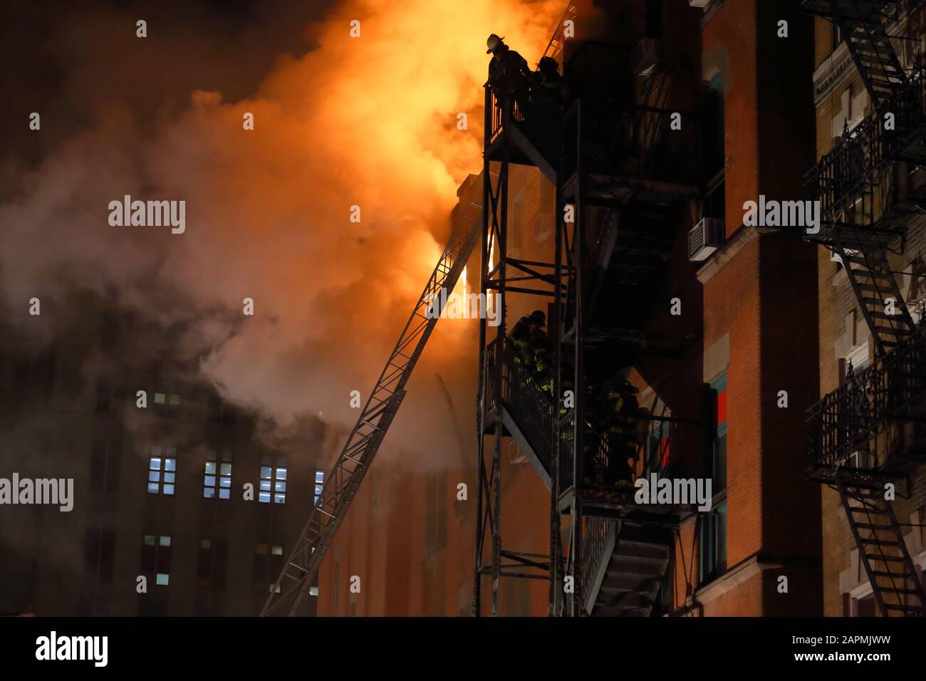 (Nueva York, NY, 23 de enero de 2020) 9pm. Bomberos en la parte superior de un escape de fuego de un centro de la comunidad en el fuego en 70 Mulberry St. El fuego estalló en el 4t Foto de stock