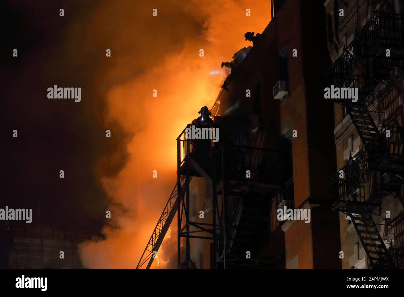 (Nueva York, NY, 23 de enero de 2020) 9pm. Los bomberos en la parte superior de una salida de incendios y en la azotea de un centro comunitario en el fuego en 70 Mulberry St. El fuego Foto de stock