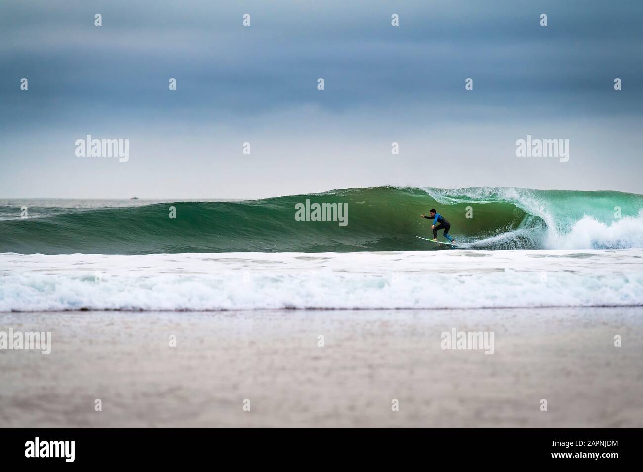 Carcavelos, Portugal - 9 de enero de 2020: Un surfista montando una ola en la playa de Carcavelos en una mañana de invierno. Foto de stock