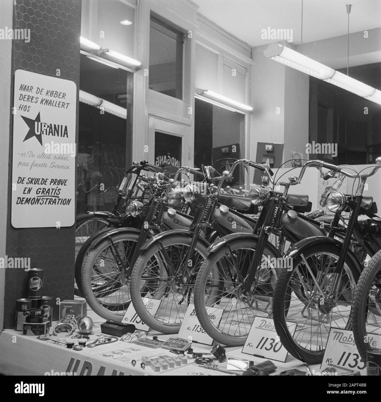 Visita a Copenhague Showcase de una tienda de bicicletas con una cartelera  para los ciclomotores de la Marca Urania Fecha: Marzo 1954 ubicación:  Dinamarca, Copenhague palabras clave: Ciclomotores, bicicletas, tiendas  Fotografía de