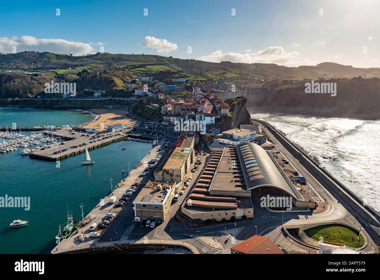 Getaria, España - Marte 11, 2019. Una vista sobre el pueblo vasco de Getaria con el puerto pesquero en primer plano y un típico lugar de surf vasco. Foto de stock