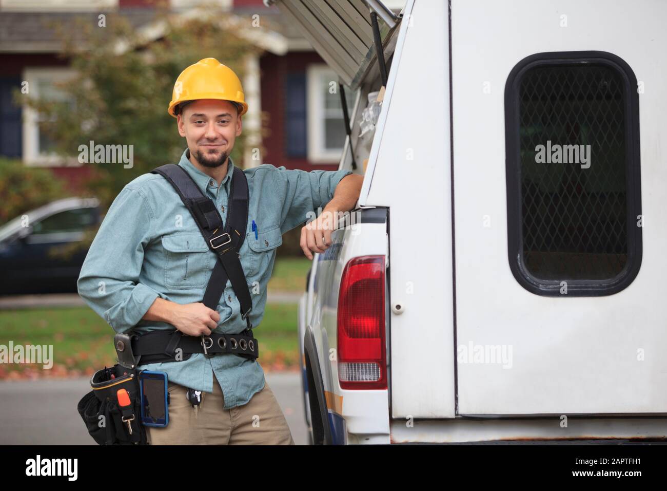 Tradesman recuperando suministros de una trampilla abierta en el lateral de su camión de trabajo Foto de stock