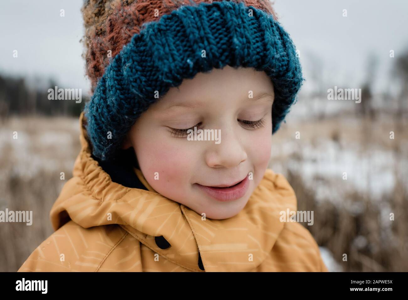 primer plano de un niño mirando hacia abajo sonriendo mientras juega fuera Foto de stock