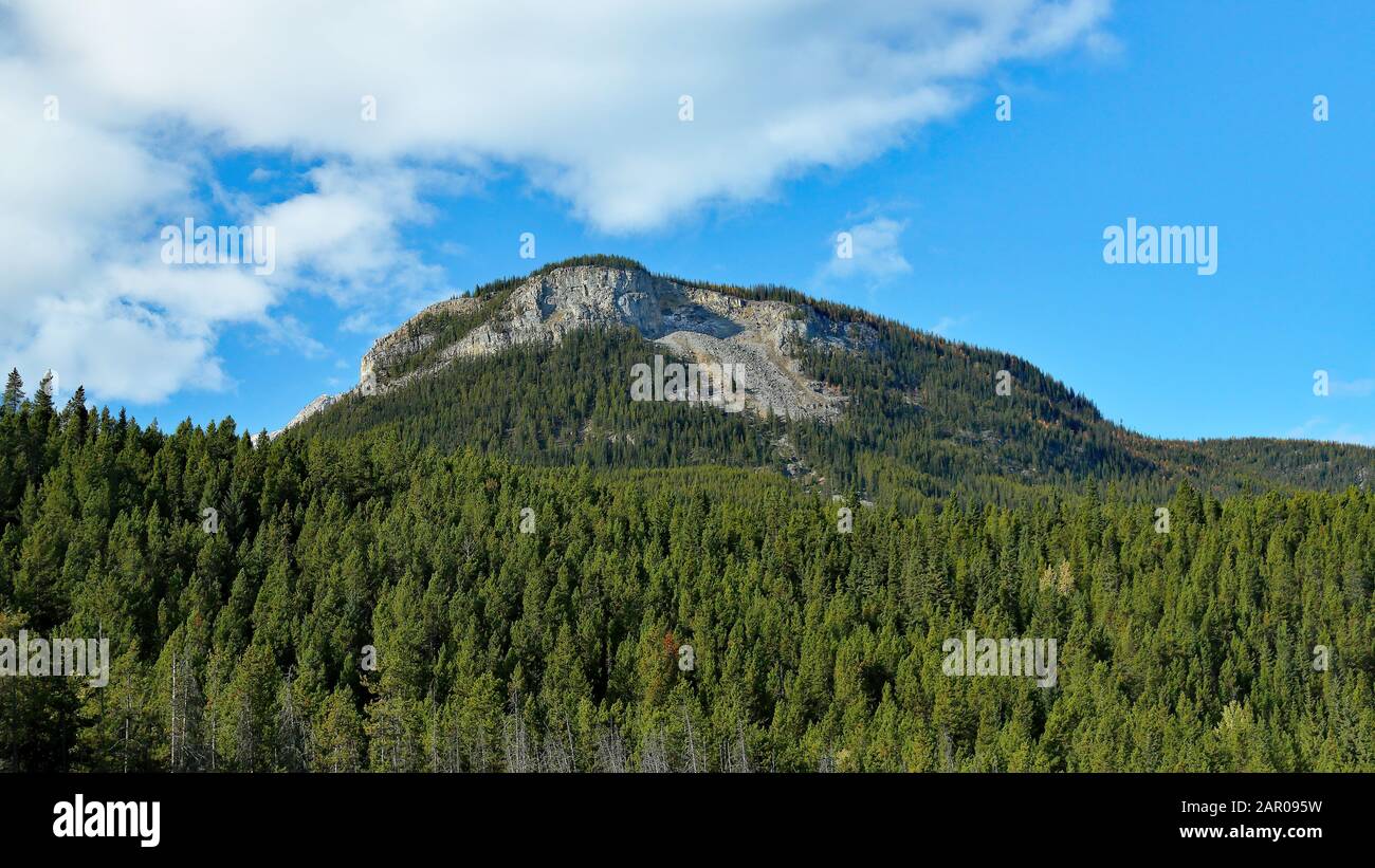 Montaña cerca del parque nacional Banff con árboles, nubes y cielo azul Foto de stock