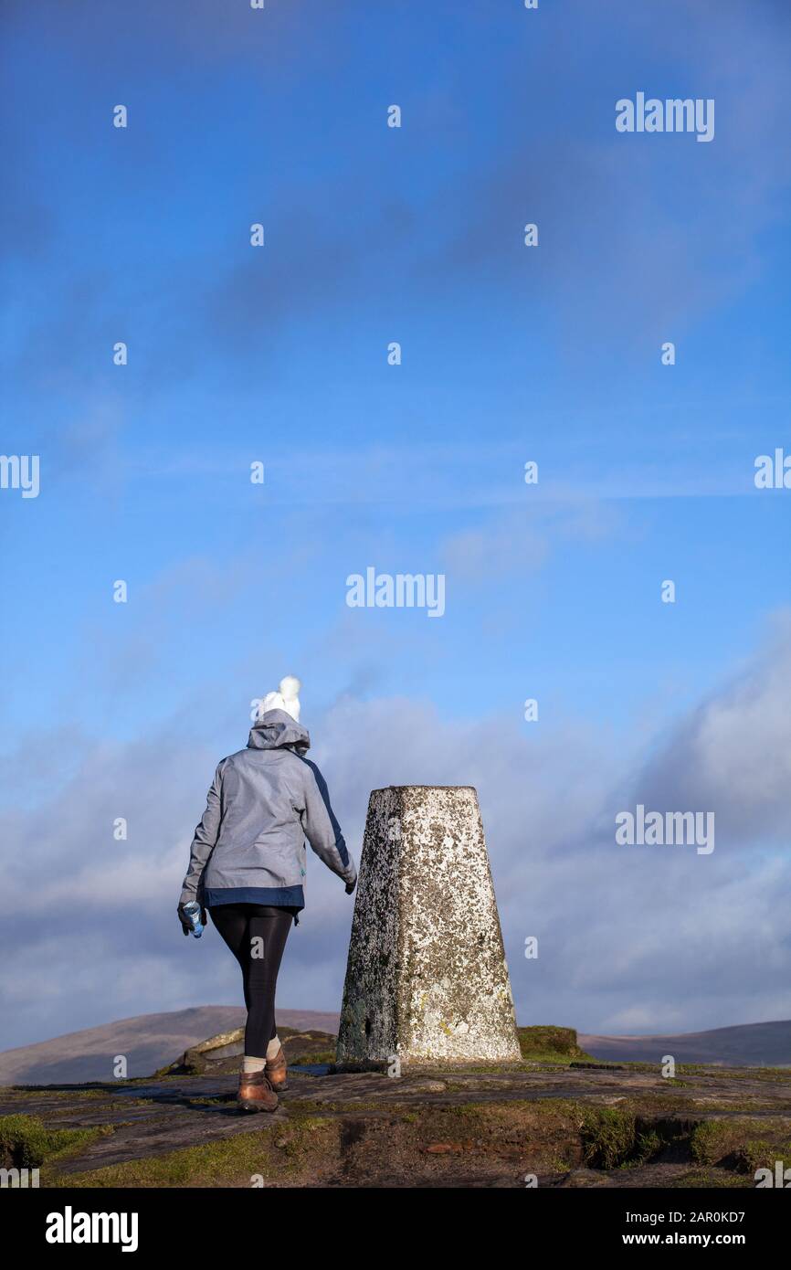 Mujer caminando hasta el punto de triangulación punto trig en la colina de Shutlingsloe en el distrito de los picos ingleses Foto de stock