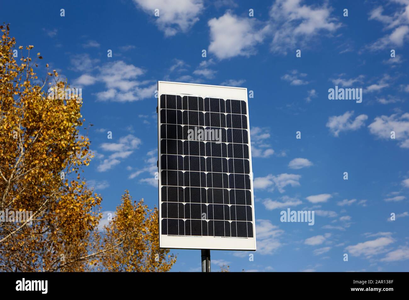 pequeño panel solar sobre poste contra cielo nublado Foto de stock