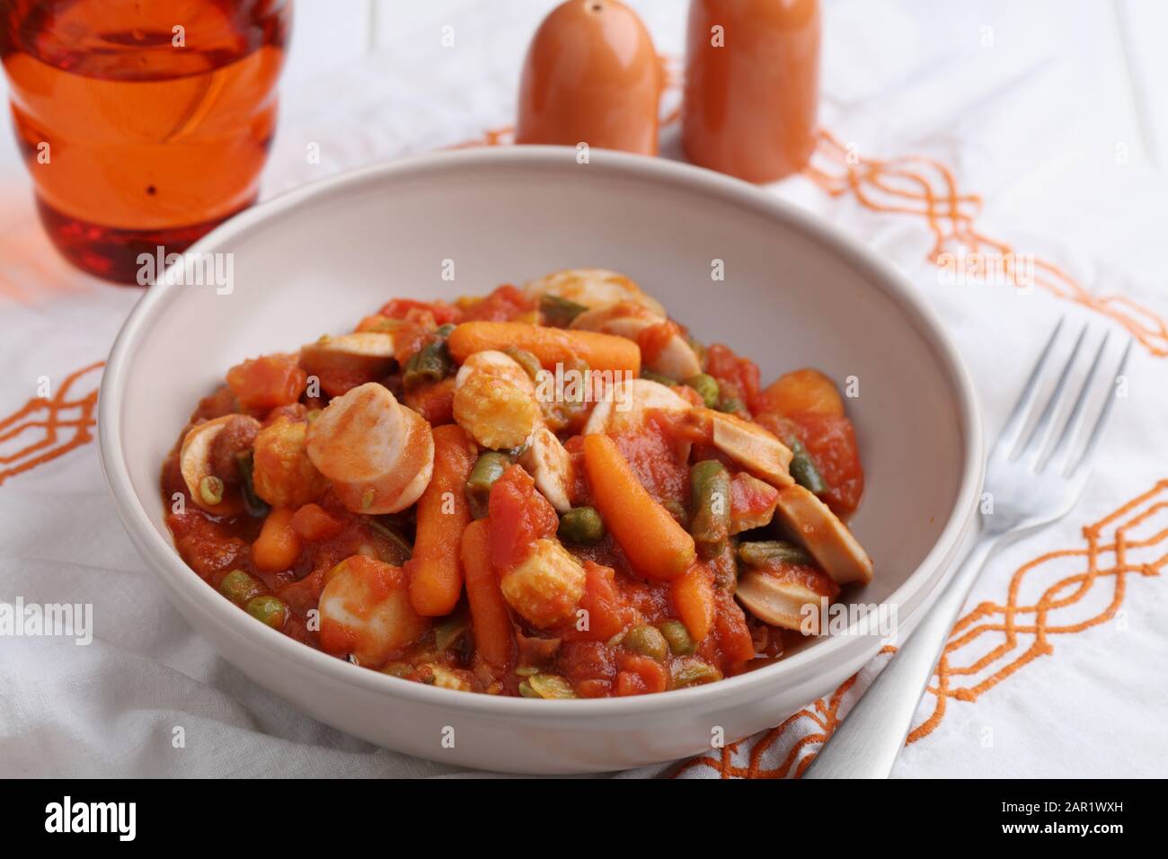 Salchicha de pollo y ragout vegetal con zanahoria, maíz, judías verdes, pimienta, guisantes verdes y salsa de tomate Foto de stock