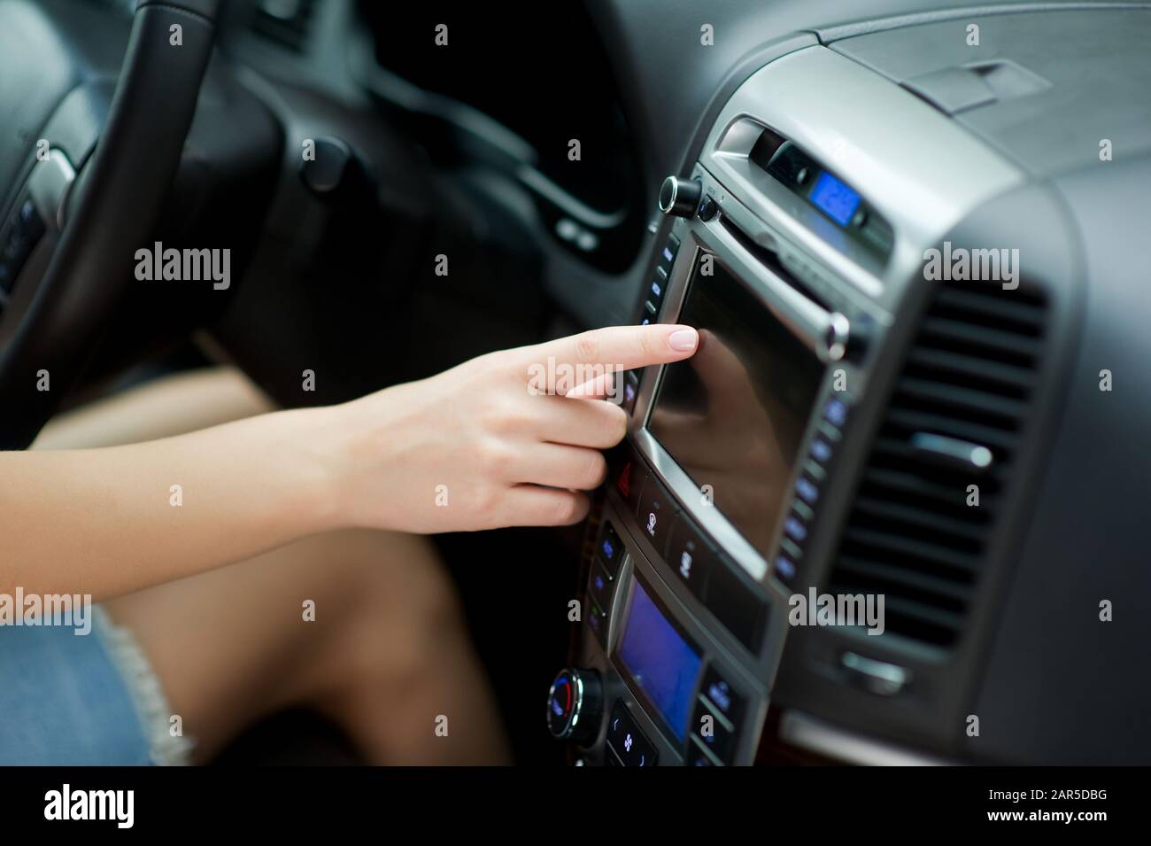 una chica sintoniza emisoras de radio mediante una pantalla táctil en el  sistema de audio del coche. Configuración de parámetros a través del  ordenador de a bordo Fotografía de stock - Alamy
