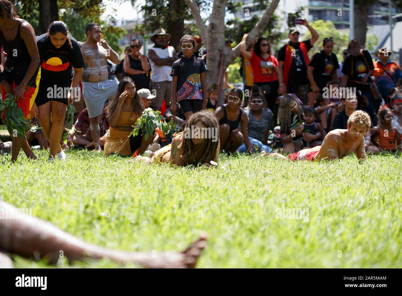 Los manifestantes realizan una danza tradicional en Musgrave Park durante el rallye.el pueblo indígena Yuggera y Turrbal organizaron un rallye conocido como Meanjin en una fecha que es sinónimo del comienzo del gobierno colonial británico y la opresión de los aborígenes. Otros temas discutidos en la manifestación incluyeron la lucha contra la injusticia y el recuerdo de Las Generaciones Robadas y la soberanía aborigen. Foto de stock