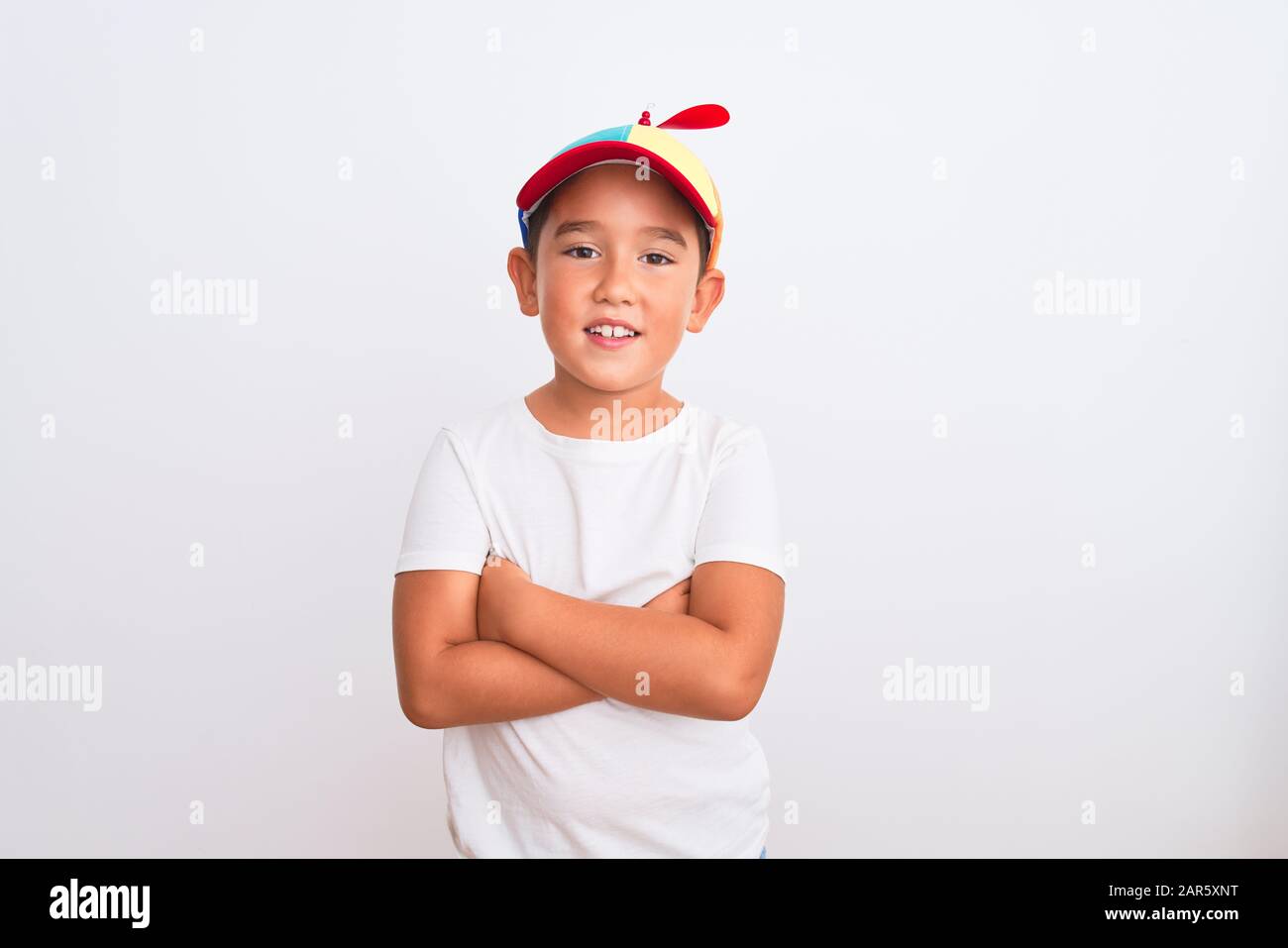 Bonito niño vestido con una gorra de colores abuelita con hélice sobre fondo blanco cara feliz sonriendo con brazos cruzados mirando a la cámara Fotografía de stock - Alamy