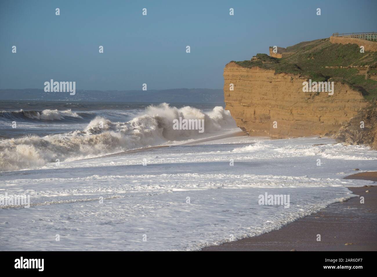 Rompedores blancos de una tormenta de canal golpeando y erosionando la playa y los acantilados de arenisca en Hive Beach, cerca de West Bay, Dorset, enero Foto de stock