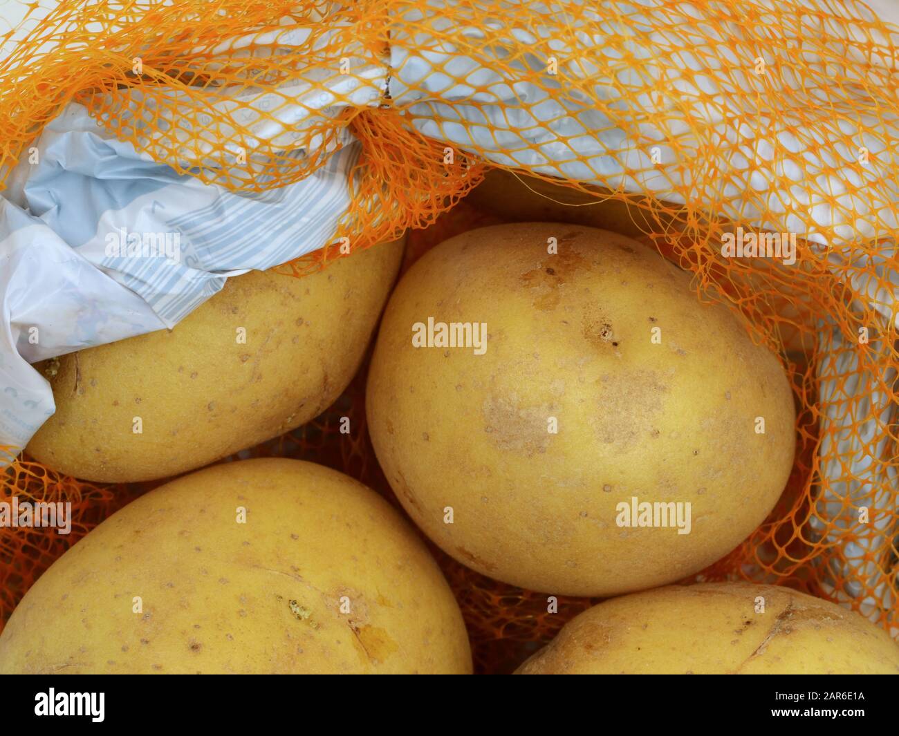 Patatas en una bolsa de red naranja o paquete de plástico, cierre Foto de stock