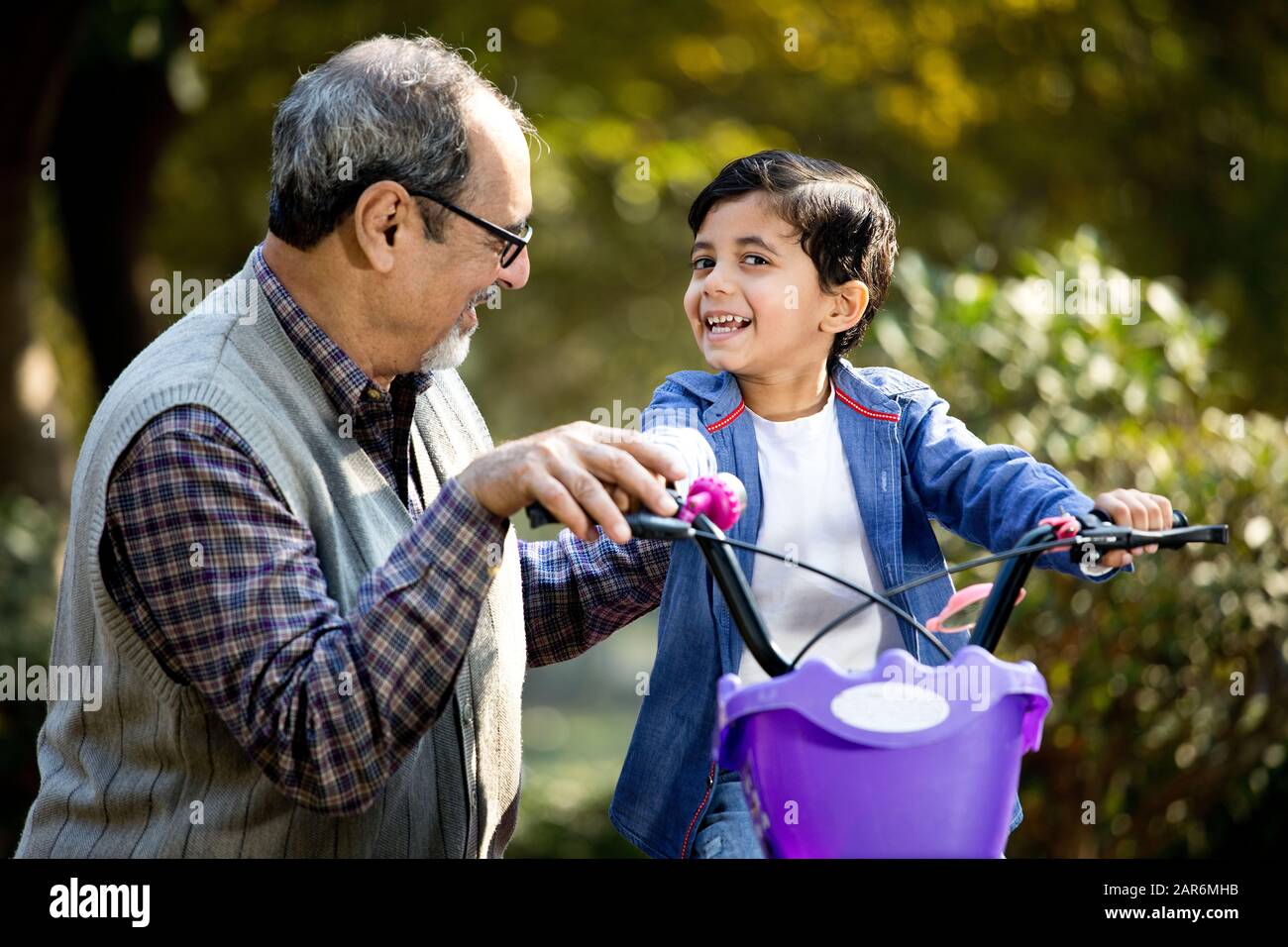 Abuelo enseñando a su nieto ciclismo en el parque Foto de stock