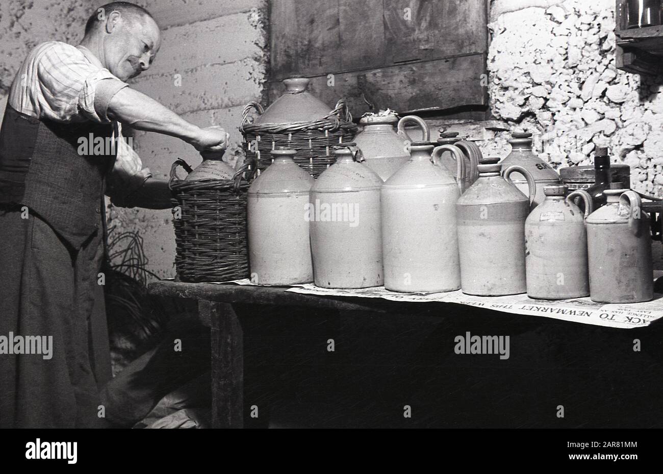 mead, un hombre en su sótano poniendo el corcho en una botella de gres