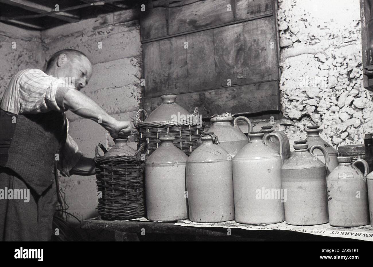 mead, un hombre en su sótano poniendo el corcho en una botella de gres