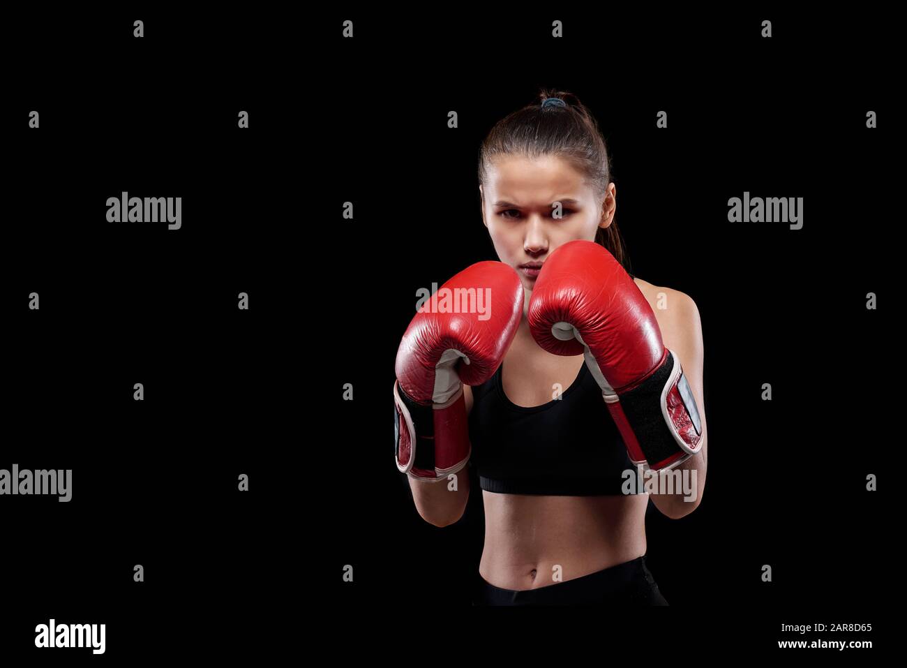 Mujer joven seria y poderosa en guantes de activo y boxeo mirando a usted Foto de stock
