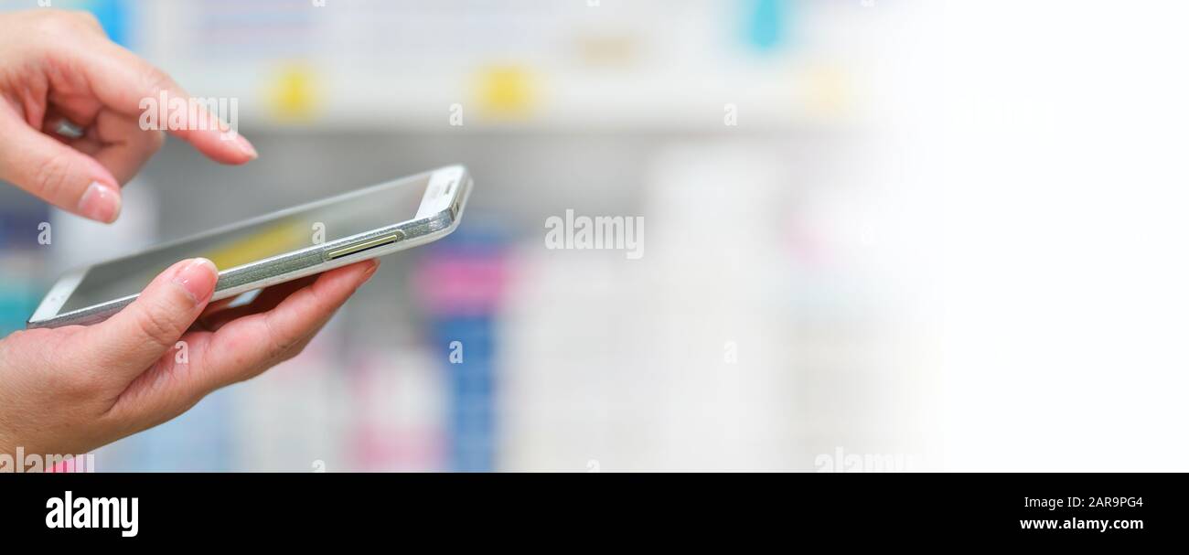 Farmacéutico uso móvil smartphone para buscar barra en la pantalla en farmacia farmacia estantes antecedentes.Online concepto médico. Foto de stock