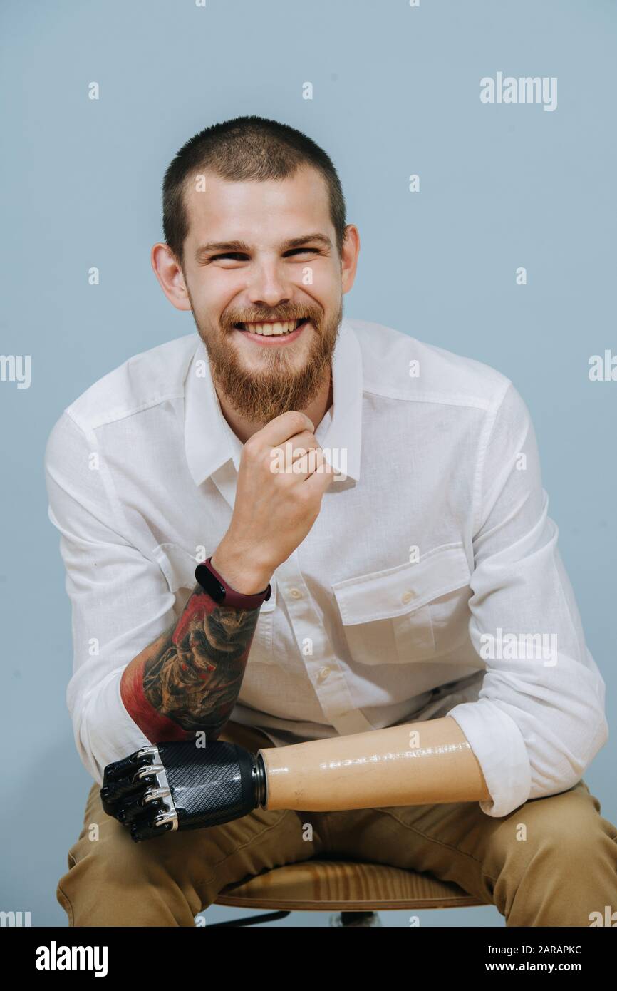 Retrato de un alegre hombre feliz con brazo biónico protésico sobre fondo azul Foto de stock