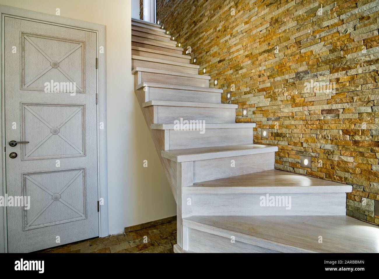 Elegante escalera contemporánea de madera en el interior de la casa loft. Pasillo moderno con paredes decorativas de ladrillo de piedra caliza y escaleras de roble blanco. Foto de stock