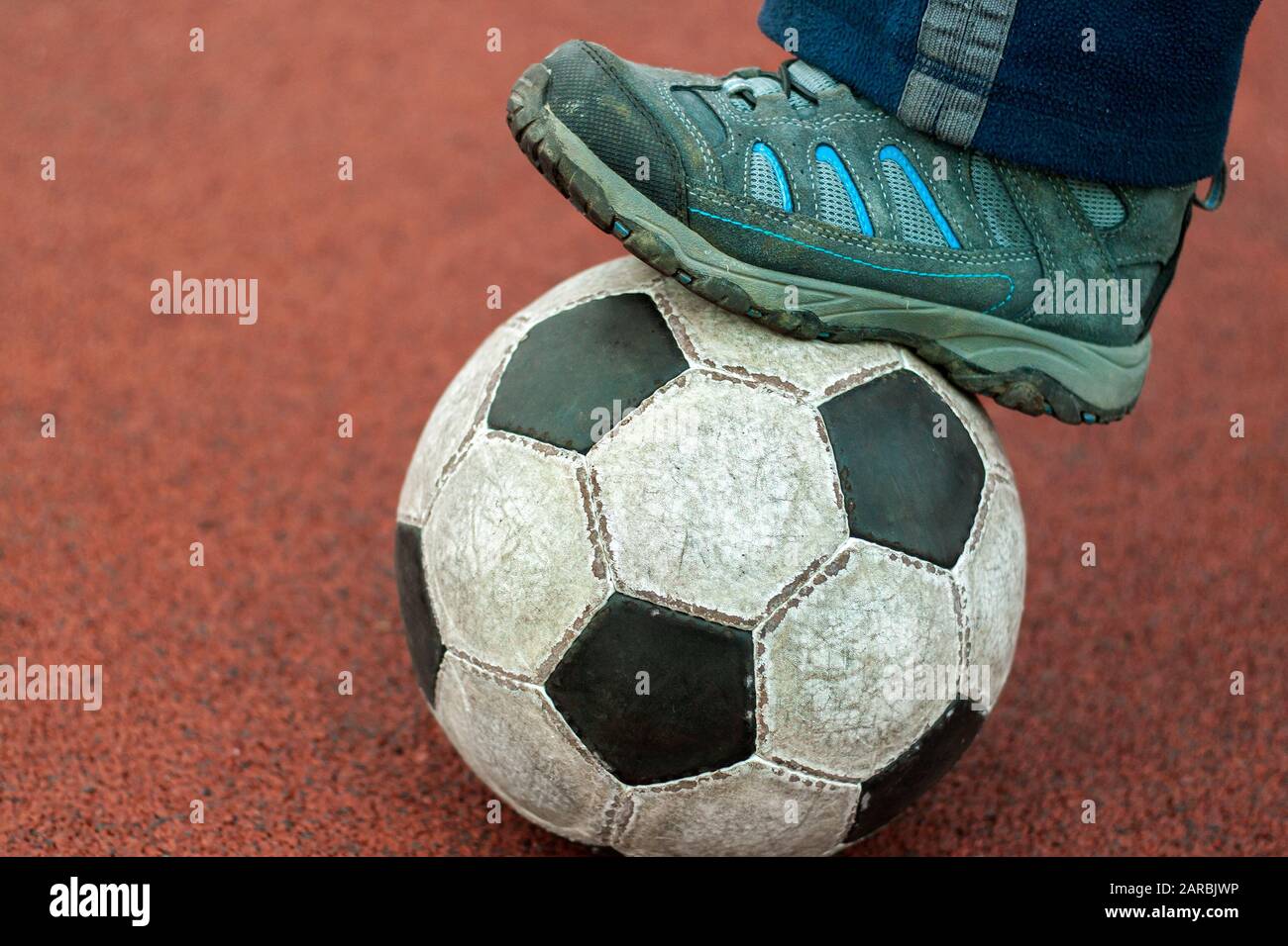 El pie humano en un sucio zapatilla en una vieja pelota de fútbol  Fotografía de stock - Alamy