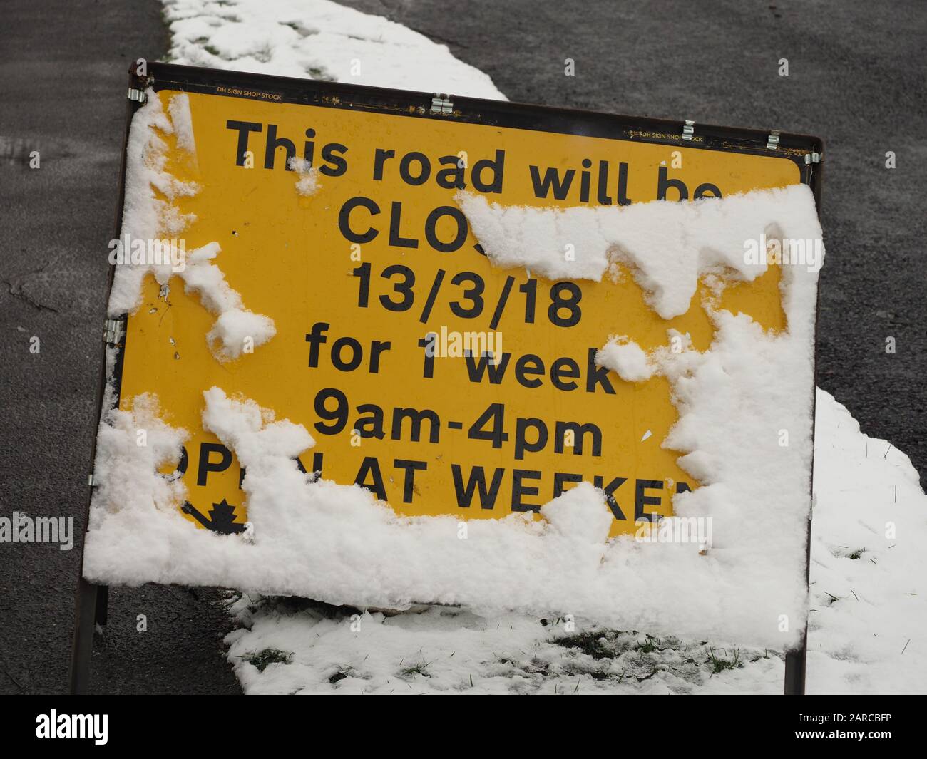 una señal de cierre temporal de la carretera cubierta por la mitad de nieve Foto de stock