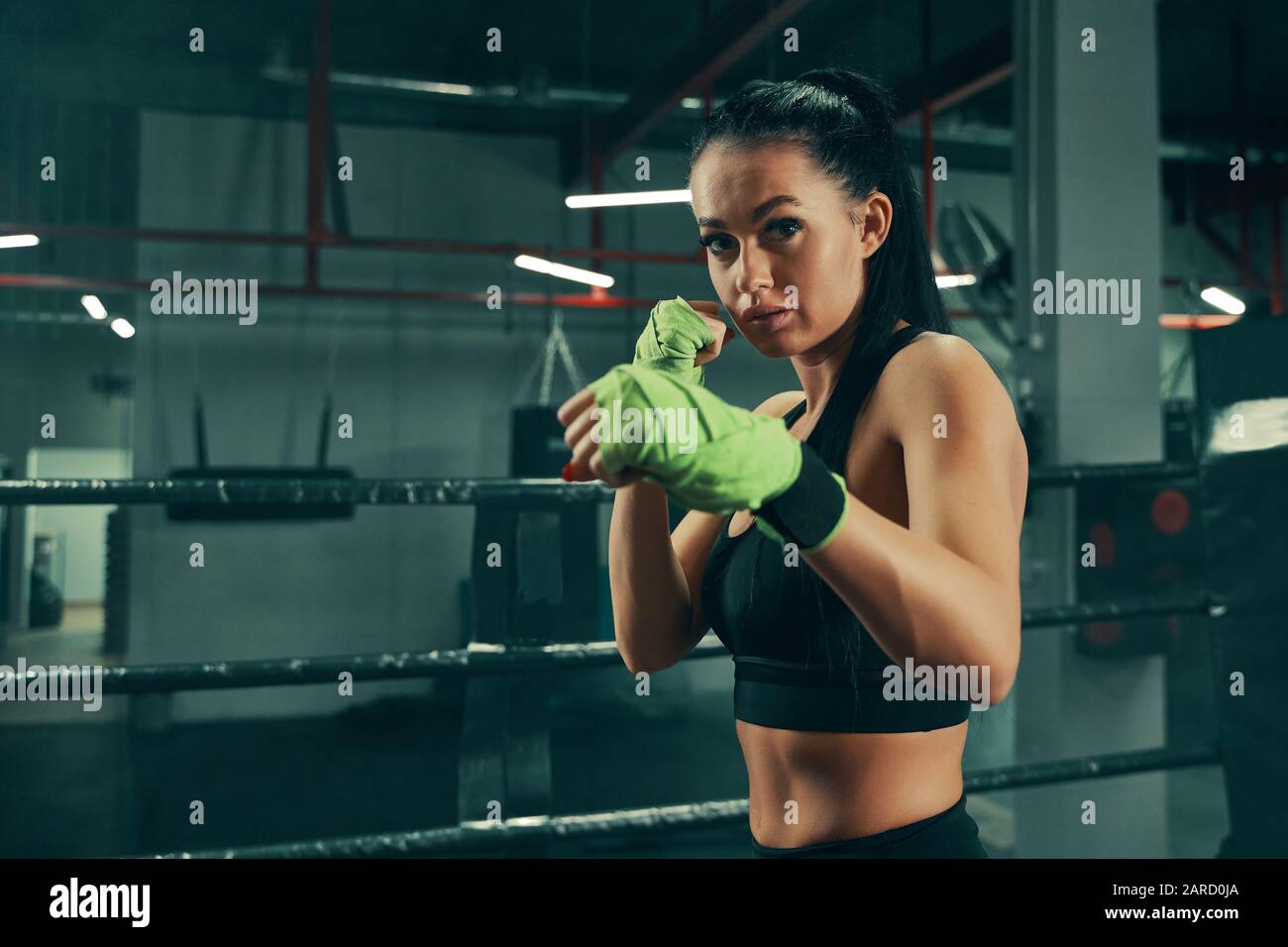 Mujer atlética durante la lucha contra el entrenamiento en el anillo de  boxeo usando vendas verdes en las manos Fotografía de stock - Alamy