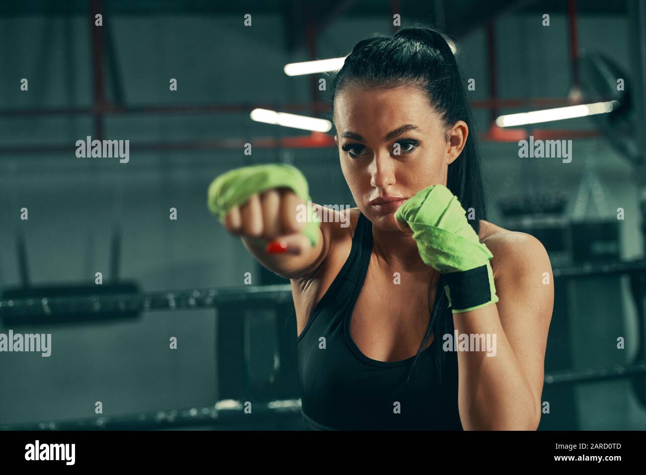 Mujer atlética durante la lucha contra el entrenamiento en el anillo de  boxeo usando vendas verdes en las manos Fotografía de stock - Alamy