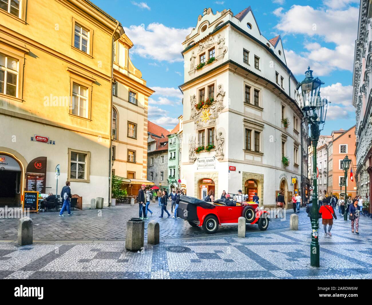 Una encantadora y pintoresca escena callejera y un coche de época en una colorida zona de tiendas, hoteles y cafés en la parte del casco antiguo de Praga, República Checa. Foto de stock