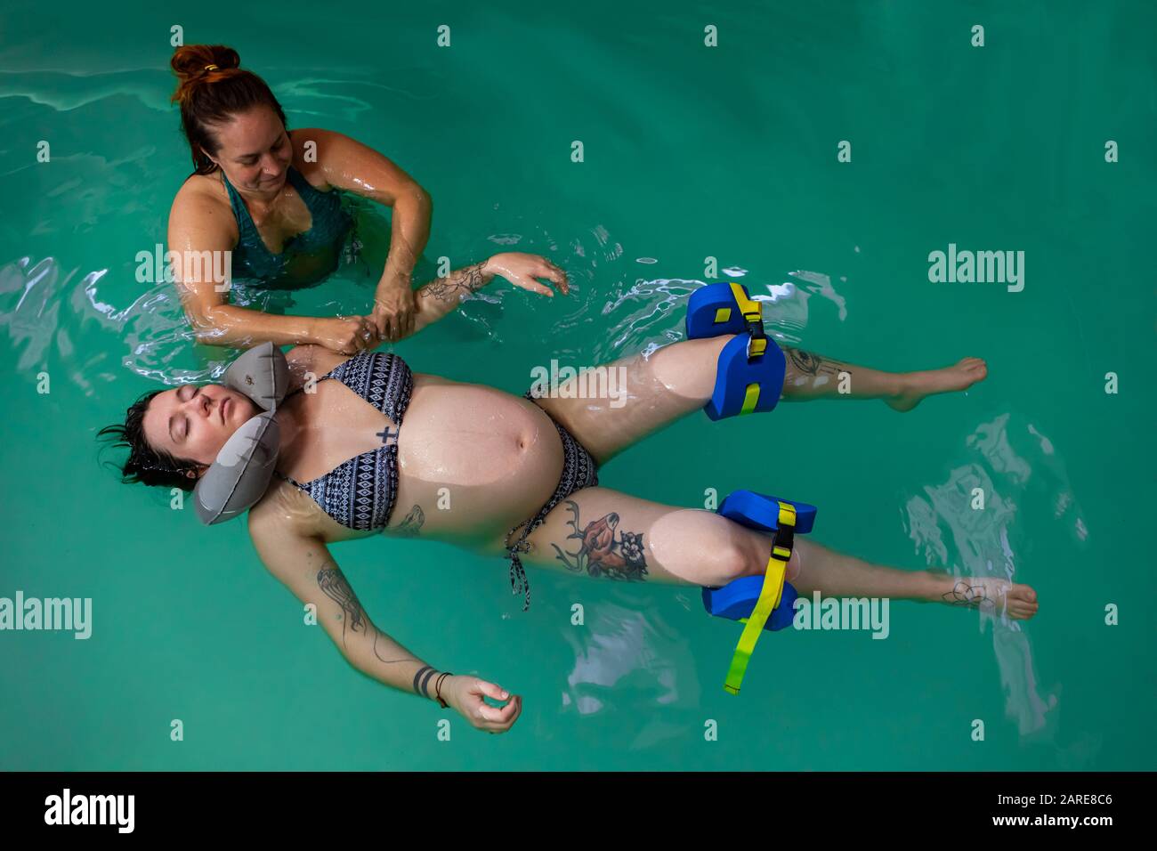 Vista de ángulo alto de mujer embarazada relajada con almohada de cuello de  goma alrededor de su cuello recibiendo masaje de agua en la piscina con  terapeuta Fotografía de stock - Alamy