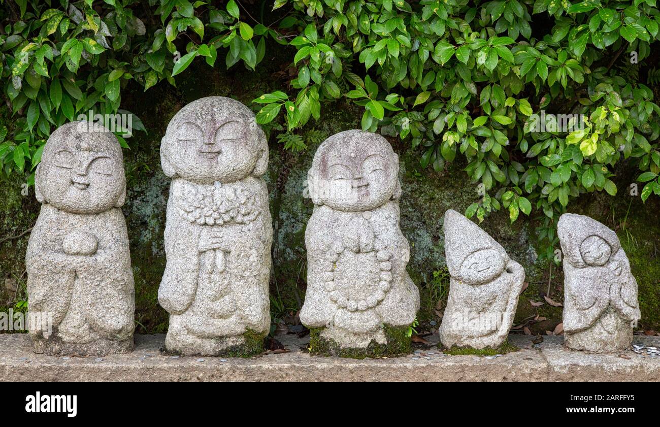 Pequeñas monedas se dejan en antiguas estatuas del templo de monjes budistas. Estas estatuas muy pequeñas se sientan en el pavimento fuera del Templo Arashiyama en Kyoto, Japa Foto de stock
