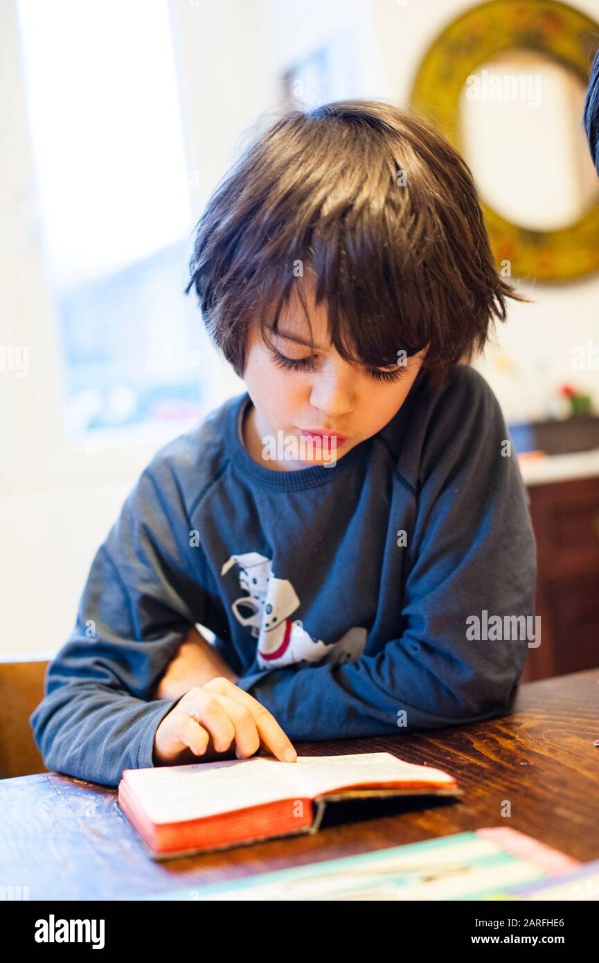 El niño sentado en la mesa de la cocina lee el libro de oraciones en latín  Fotografía de stock - Alamy