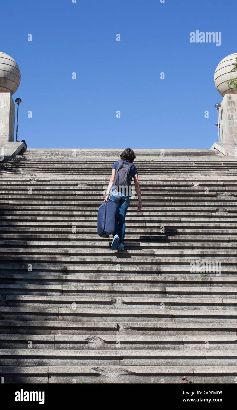 Mujer jóvenes turistas subiendo las escaleras con su maleta pesada. Barreras de accesibilidad de distritos históricos concepto. Foto de stock