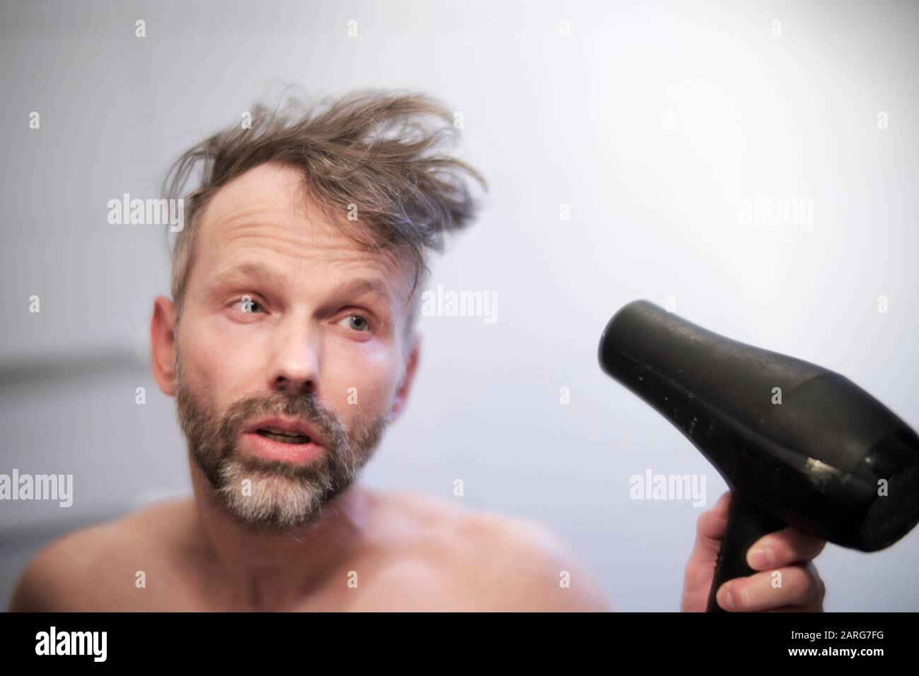 Hombre usando secador de pelo Fotografía de stock - Alamy