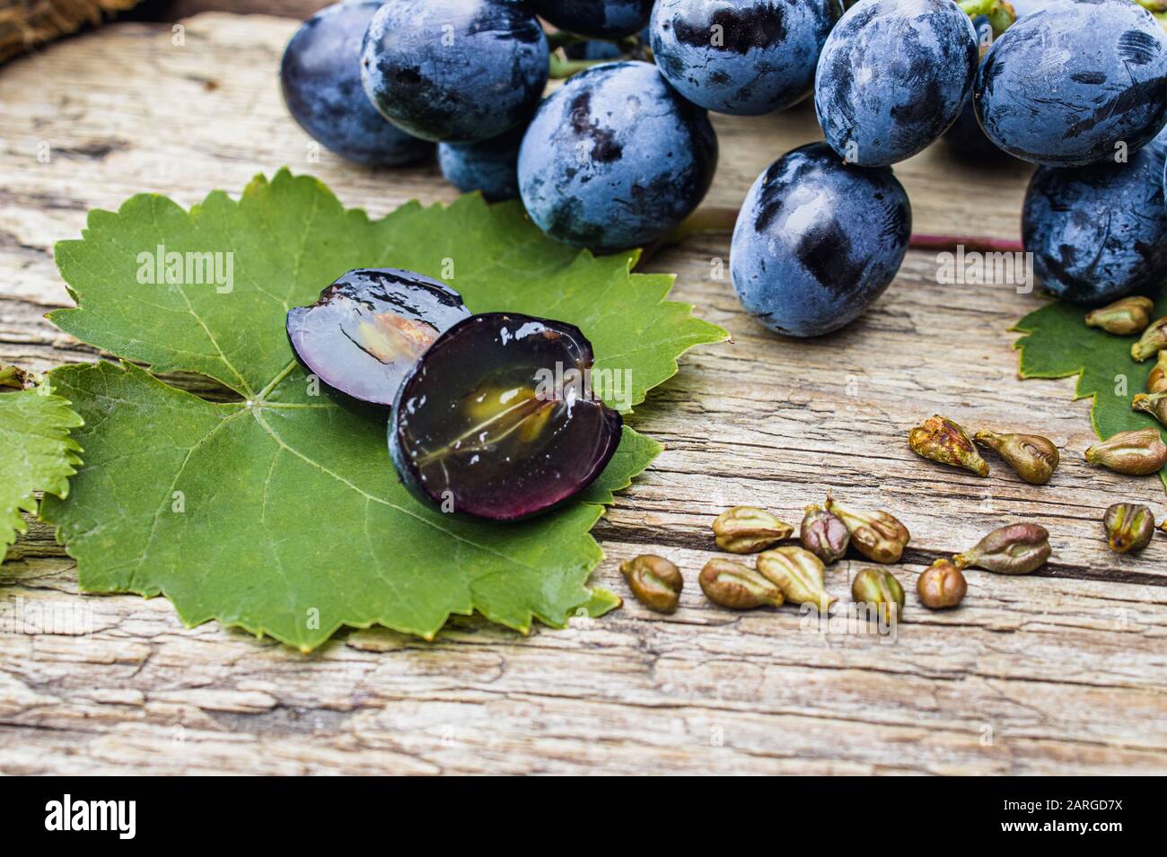 Uvas y semillas de uva en una hoja verde en tablas de madera antiguas. Uva  azul. Spa, bio, concepto de productos ecológicos Fotografía de stock - Alamy