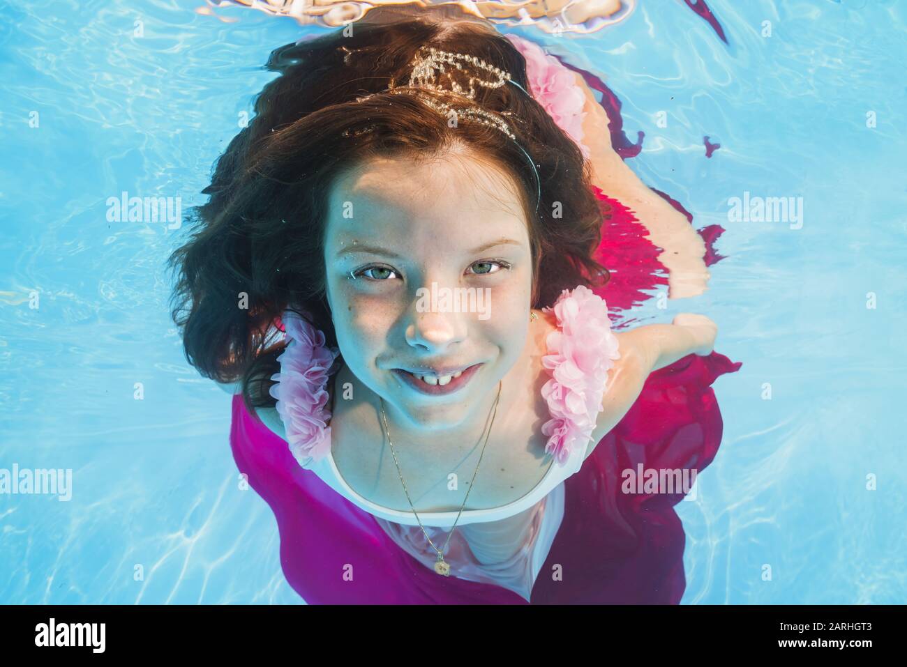 Graciosa chica en vestidos de rosa con poses bajo el agua. Una joven y hermosa chica se posan bajo el agua en la piscina. Foto de stock