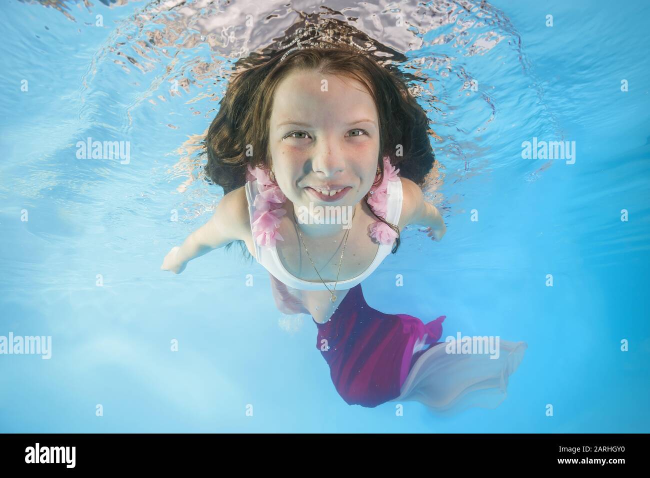 Graciosa chica en vestidos de rosa con poses bajo el agua. Una joven y hermosa chica se posan bajo el agua en la piscina. Foto de stock