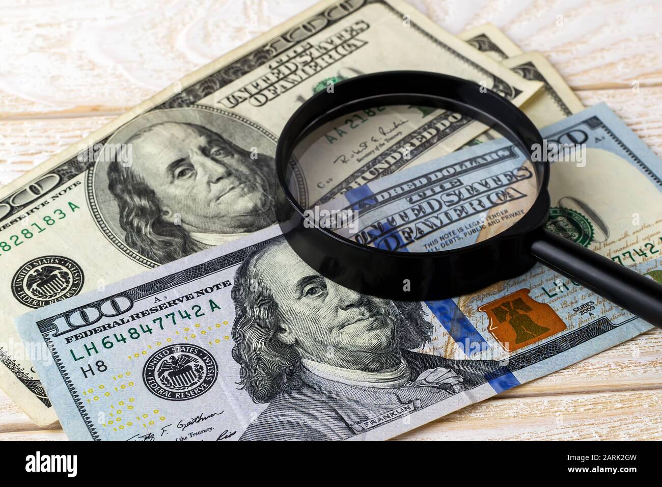 Lupa sobre billetes nuevos y viejos en una superficie de madera blanca. Compruebe la autenticidad del dinero. Concepto de riqueza, pobreza y falsificación de dinero Foto de stock