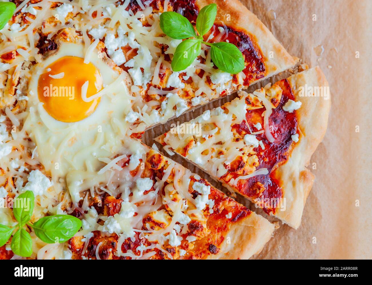 Un golpe de pizza con huevo, queso y hierbas. Escena rústica y luz dramática. Foto de stock