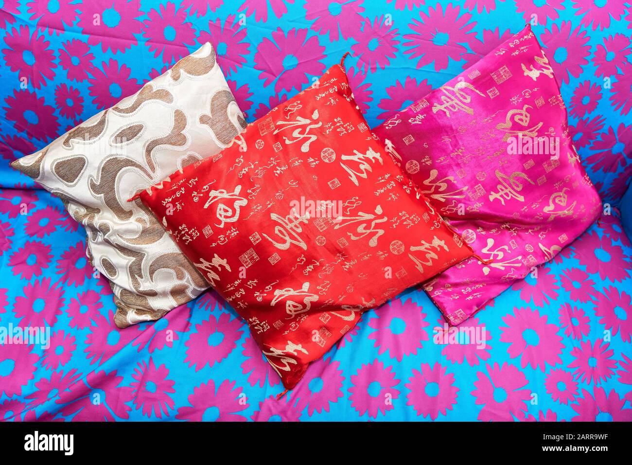 Ibajay, provincia de Aklan, Filipinas: Tres almohadas de colores pequeños sobre un sofá, de color azul con motivos florales rosas Foto de stock