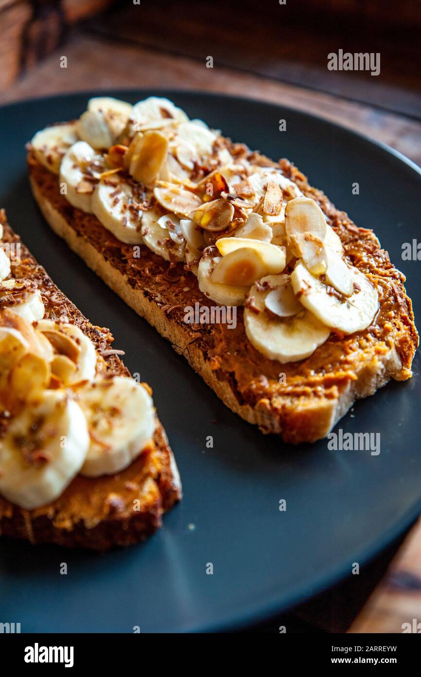 Detalle de una rebanada de pan con mantequilla de maní, miel y rebanadas de plátano Foto de stock