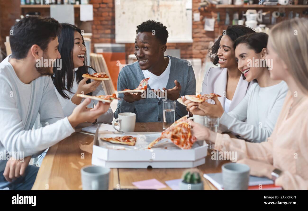 Grupo internacional de compañeros de trabajo disfrutando juntos de la pizza Foto de stock