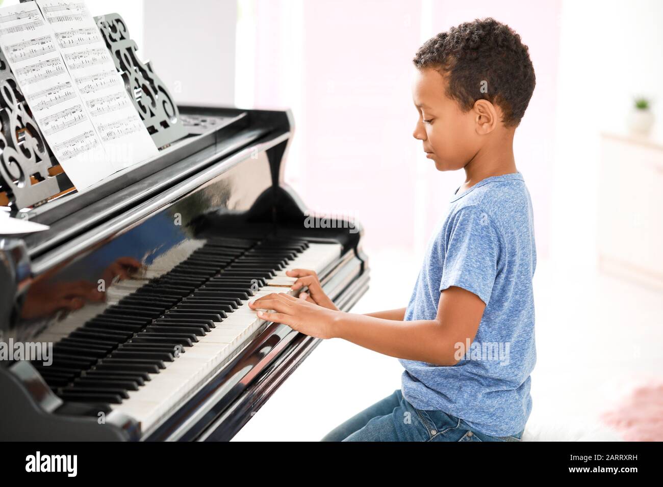 Pequeño niño afroamericano tocando el piano de cola en casa Fotografía de  stock - Alamy