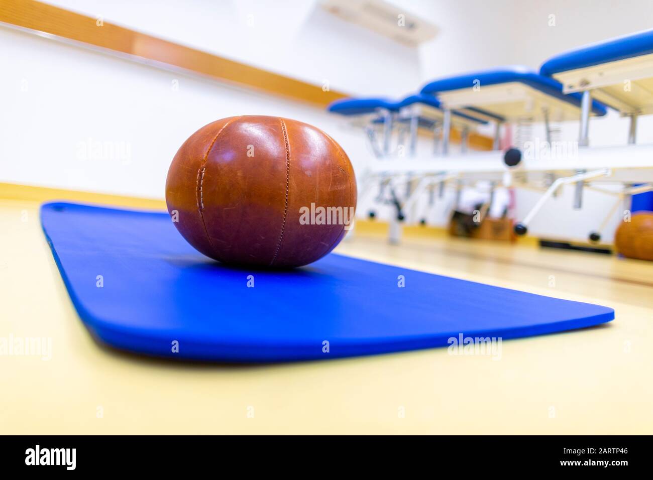 La pelota de gimnasio se encuentra en una alfombra azul Foto de stock