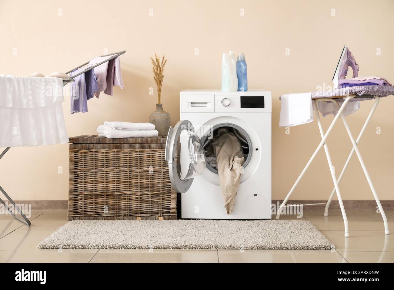 Moderna lavadora con lavandería, secadora y tabla de planchar cerca de la  pared de color Fotografía de stock - Alamy